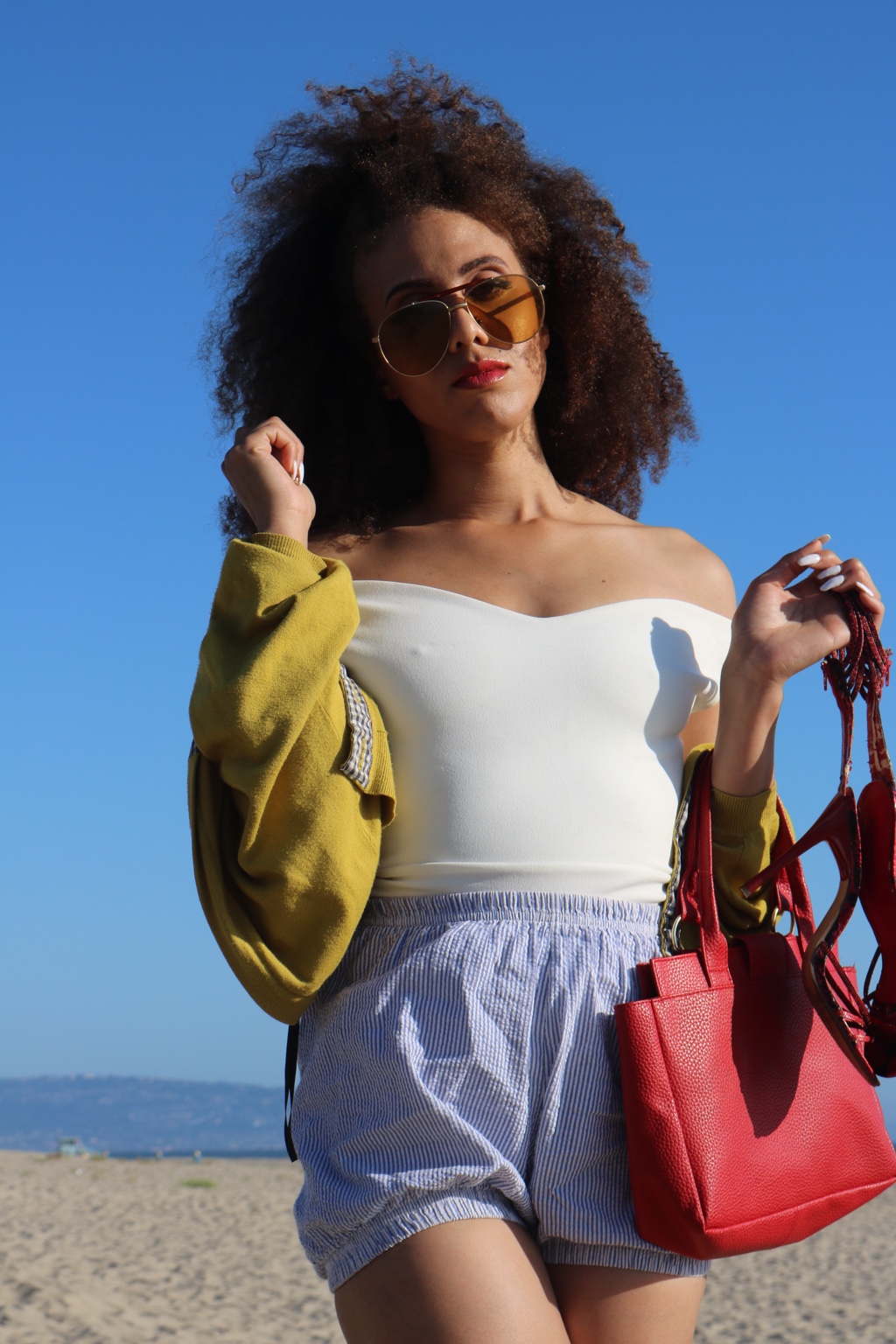 IREIGN in sunglasses on the beach under a bright blue sky